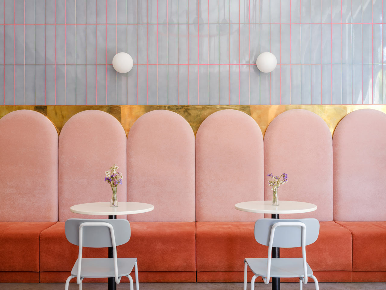 pink and orange banquette with gold against gray tile wall