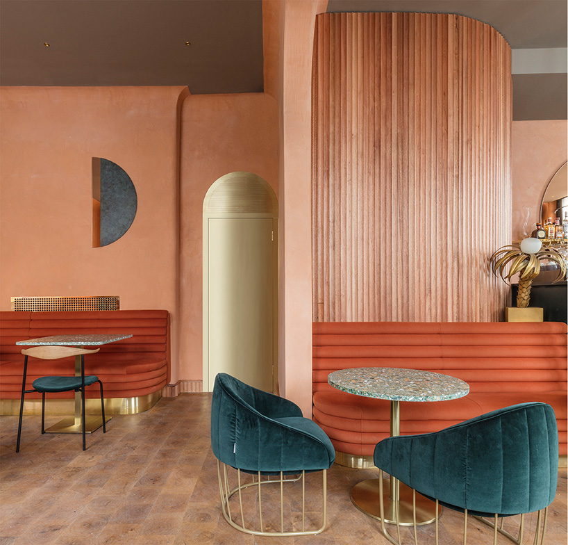 coral walls with rust color restaurant banquette with deep teal upholstered chairs 