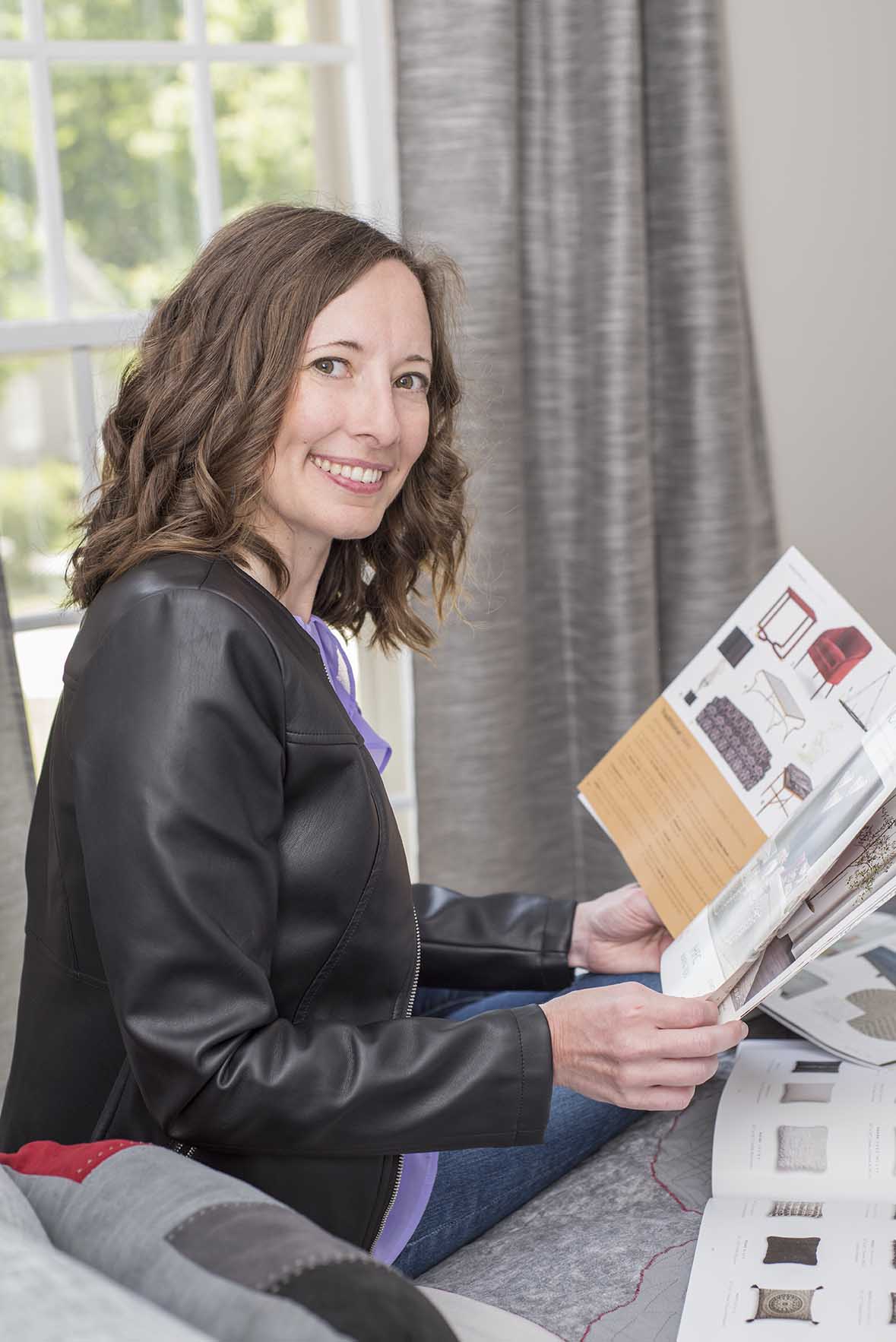 Interior designer sitting on bed, looking through design catalogues