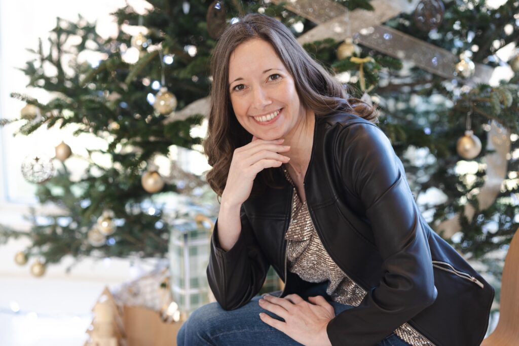 woman sitting on chair adjacent to a decorated Christmas tree