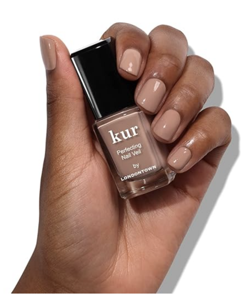 A woman's hand holding the clear nail polish bottle with brown nail polish inside. Her nails are shown in the same color.